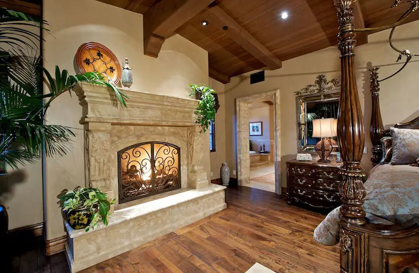 Mediterranean style master bedroom with rustic stone fireplace and four poster bed