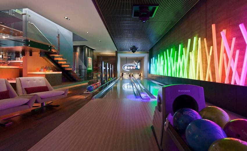 Modern basement bowling alley with neon lights small bar and modern chairs