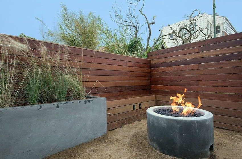Modern backyard with fine crushed gravel patio, firepit and horizontal fence with bench
