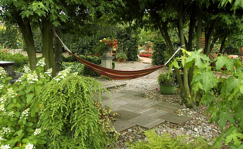Relaxing backyard with gravel and wood walkway with hammock