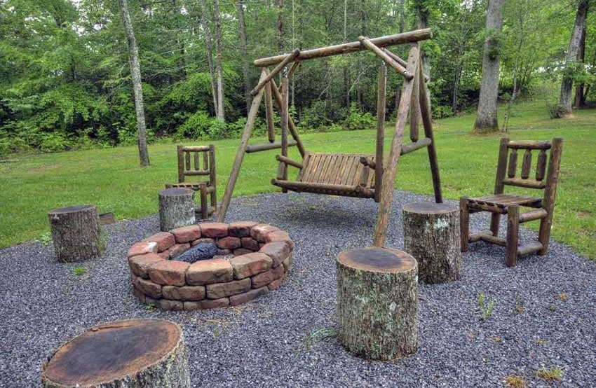 Rustic gravel patio with paver fire pit, wood log benches and wood swing
