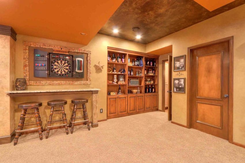 small basement with bar against wall dartboard and liquor cabinet