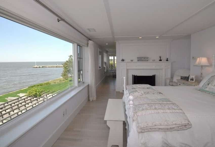 Waterfront bedroom in white with large fireplace