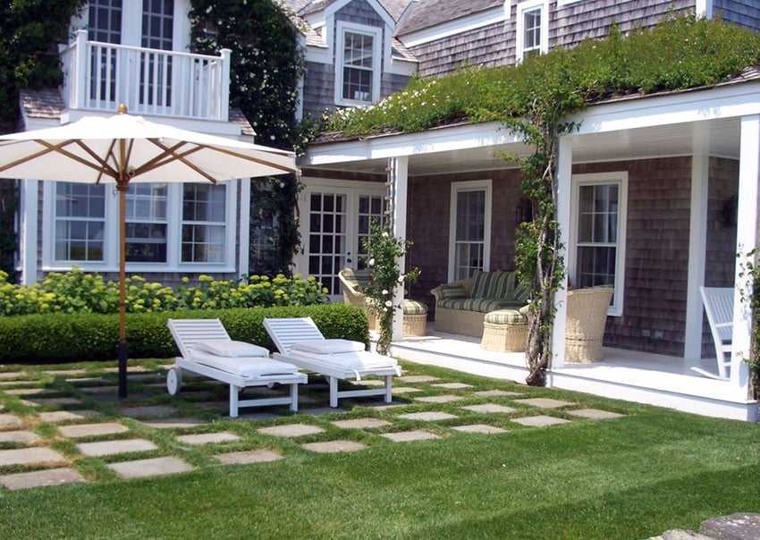 Backyard step stone patio with grass lounge chairs and umbrella