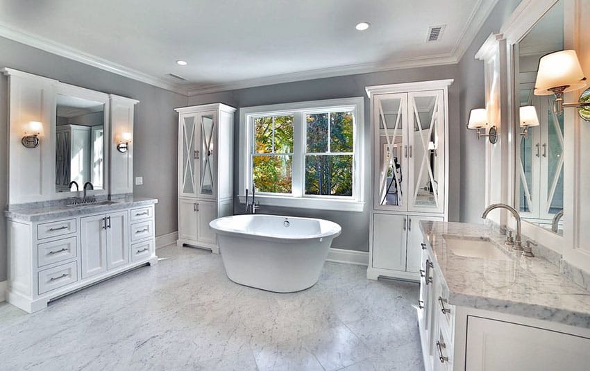 Beautiful bathroom with freestanding tub, outside views and white marble floor & countertops