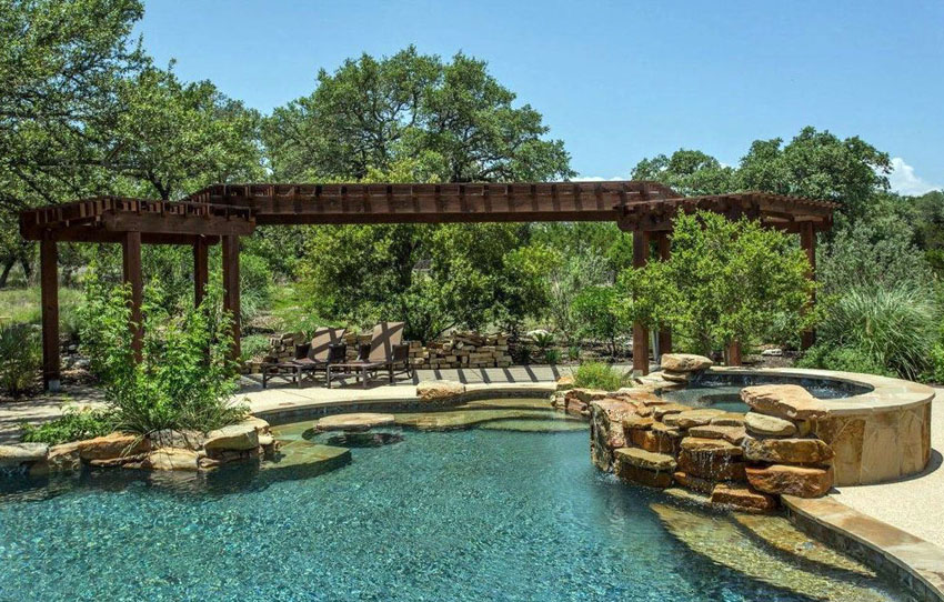 Pool with rock features and a long hallway-like pergola