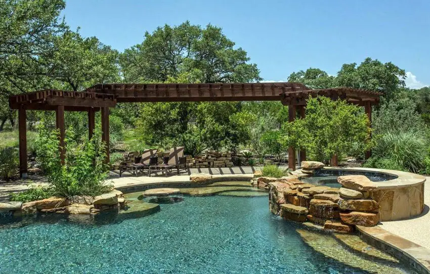 Pool with rock features and a long hallway-like pergola 