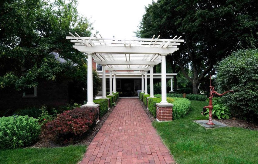 Brick walkway with white pergola with raised brick base