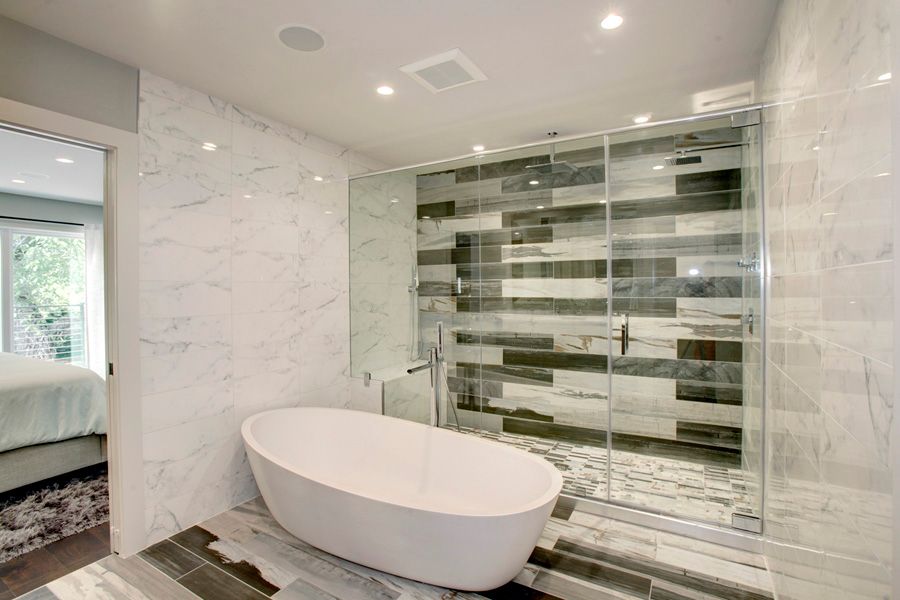 Contemporary master bathroom with large soaking bathtub, marble wall tile and porcelain shower tile
