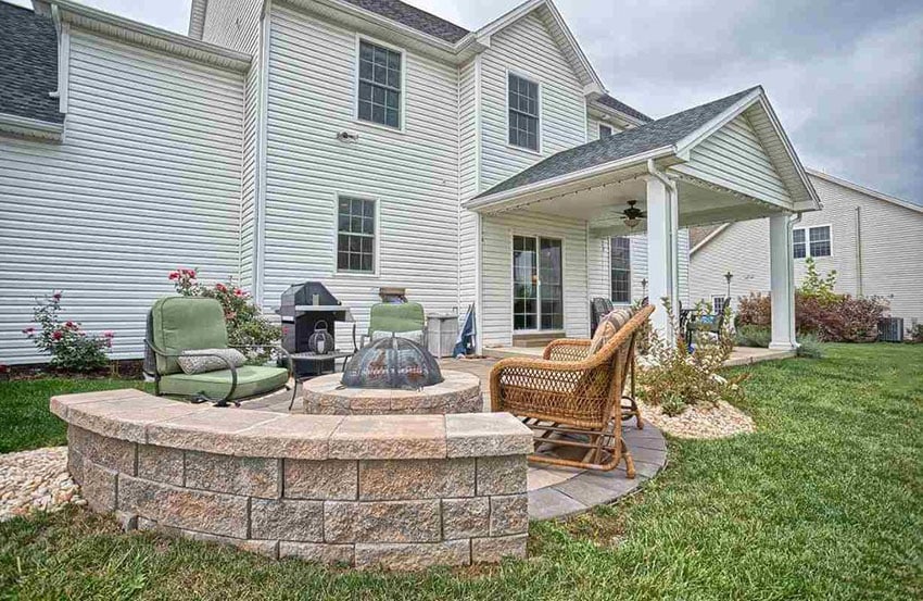 Curved stone bench around fire pit in backyard