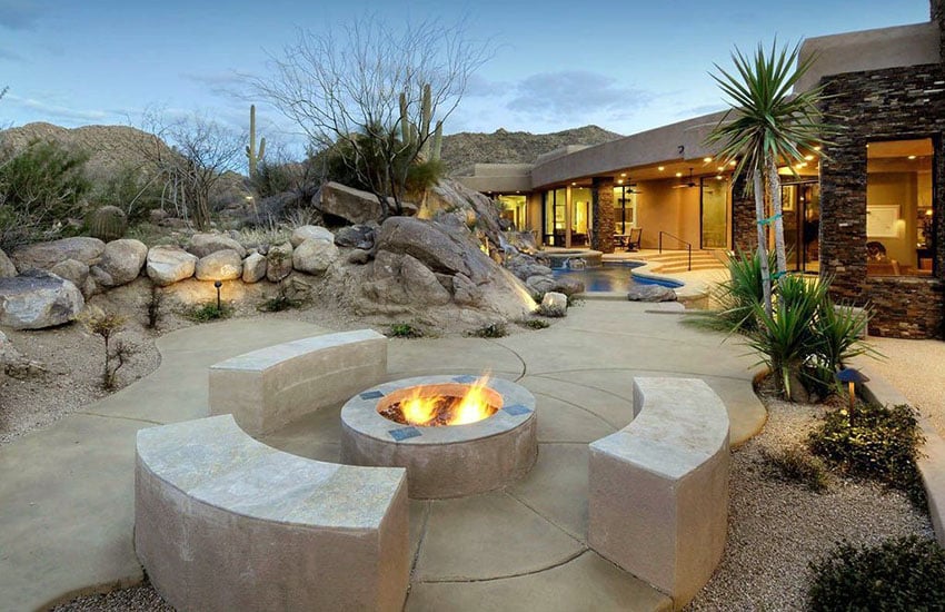Desert landscape backyard patio with cement benches around fire pit