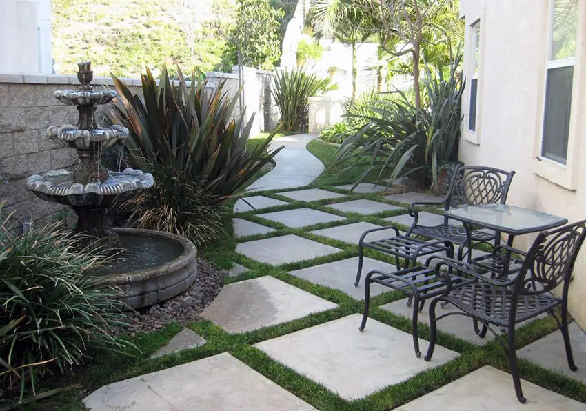 Gray concrete paver patio with grass border and backyard fountain