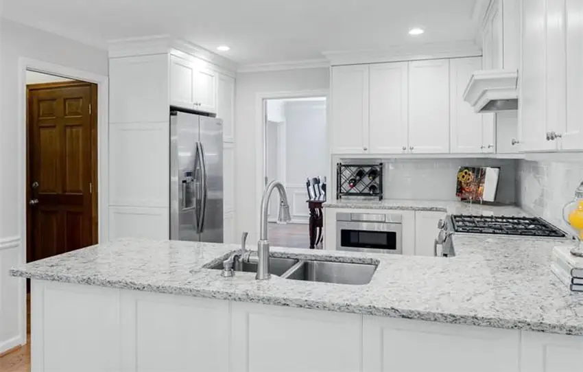 Kitchen with white alpha granite countertops with white raised panel cabinets