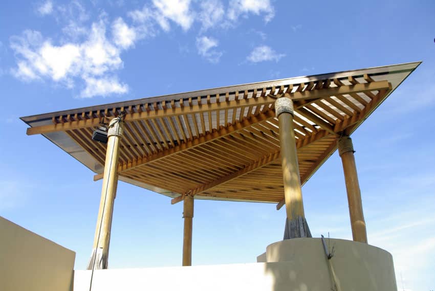 Pergola with wing shaped top and placed on solid wood trunks