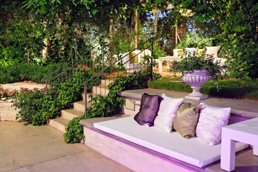 Purple concrete bench with cushions in backyard garden
