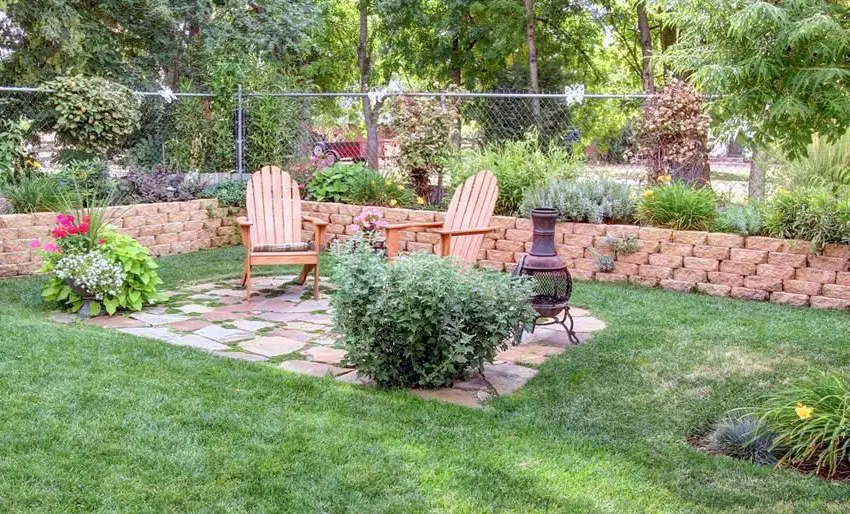 Rough flagstone patio in backyard with portable fireplace surrounded by grass