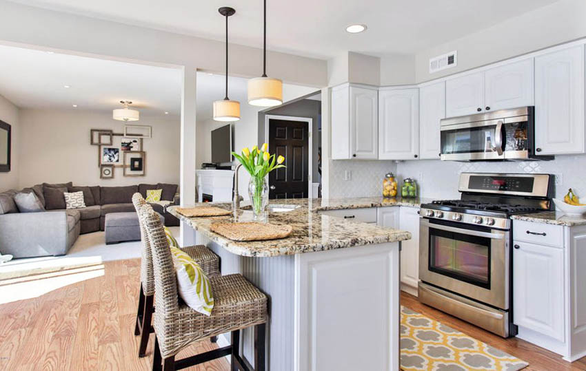 Small open plan kitchen with lattached living room, white cabinets, peninsula and beige granite countertops