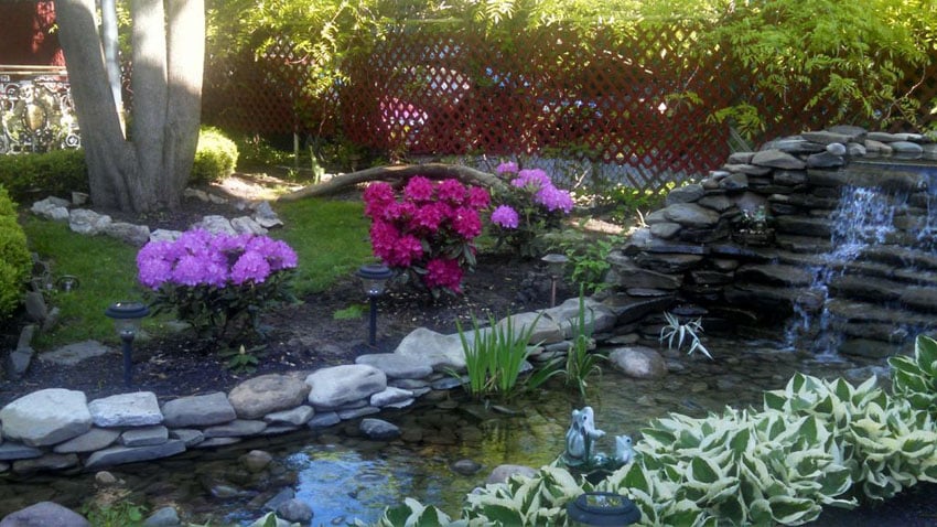 Backyard garden with stacked stone fountain with lattice fence