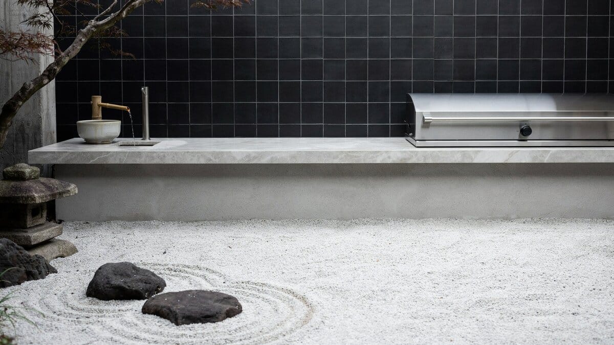 Utilitarian concrete outdoor kitchen with a built-in grill and black tiled accent wall