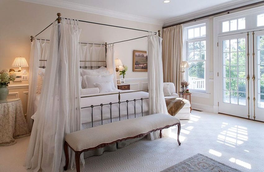 Beautiful french style bedroom with canopy bed, ottoman and french doors