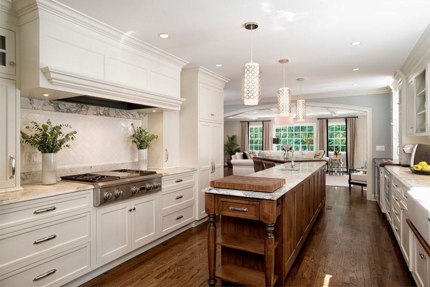 Beautiful kitchen with white cabinets and narrow center island with sink and small butchers block