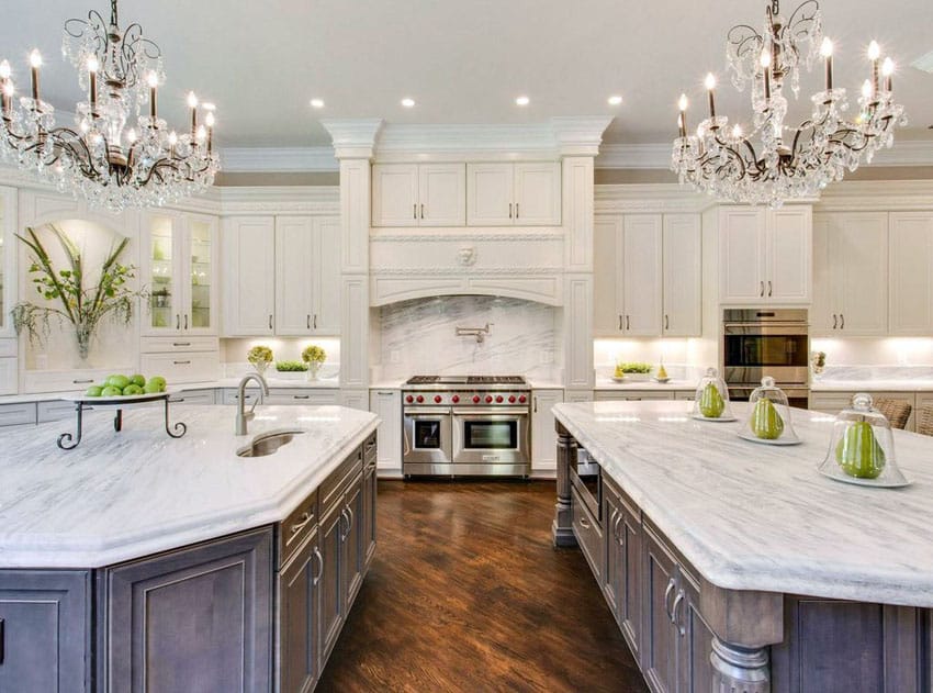 Beautiful kitchen with white cabinets two islands two chandeliers and Carrara marble countertops