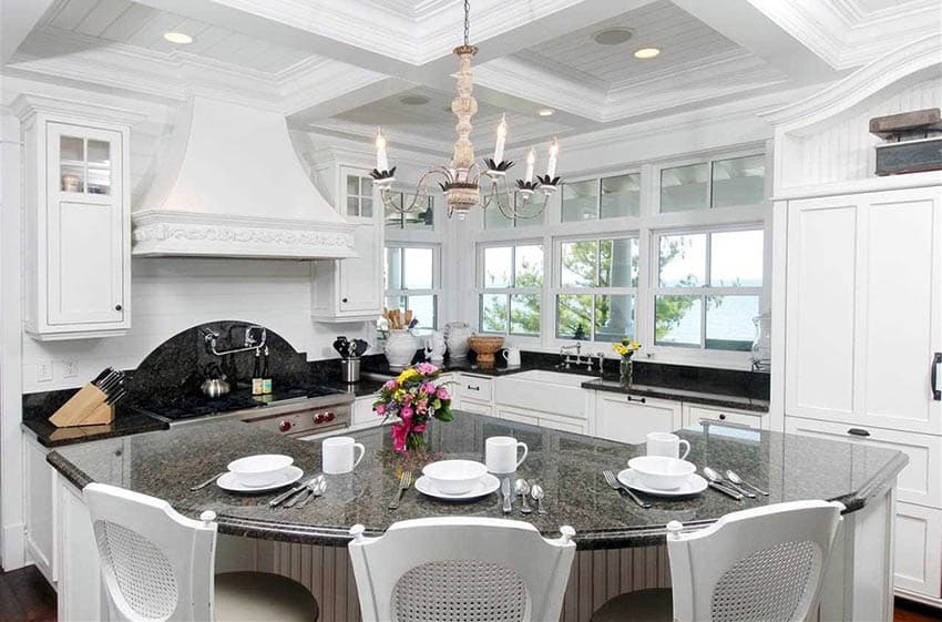 Black and white granite countertop kitchen with rounded island and white cabinets