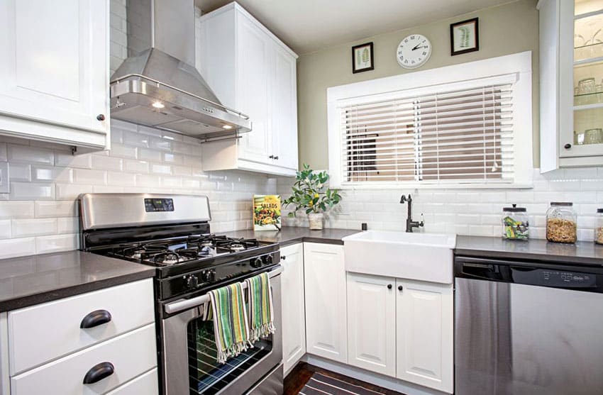 Contemporary kitchen with white raised panel cabinets, dark shiny quartz counter and glazed subway panels