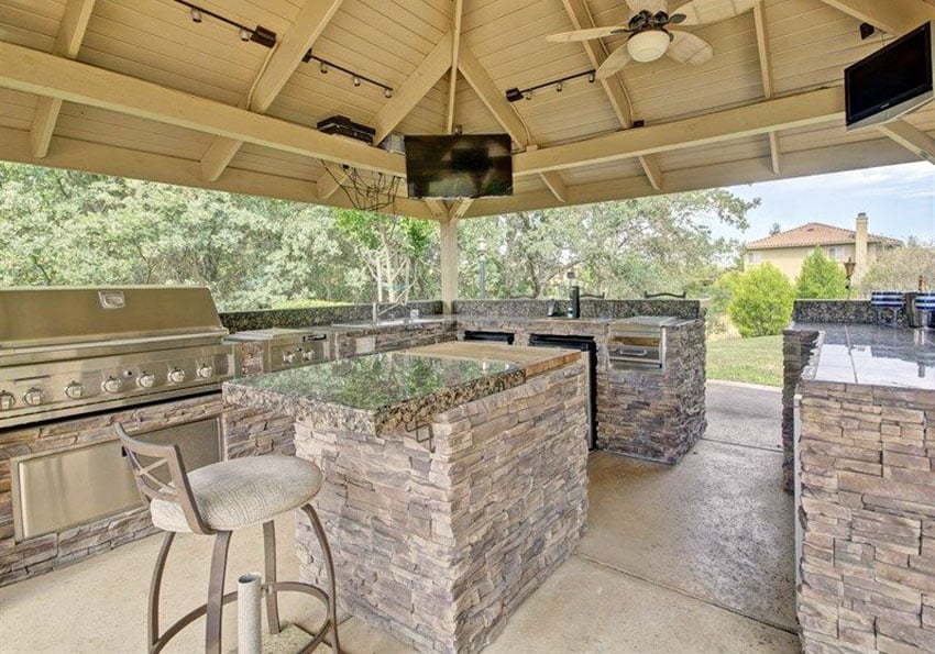 Covered outdoor kitchen with island, vaulted ceiling and stacked stone