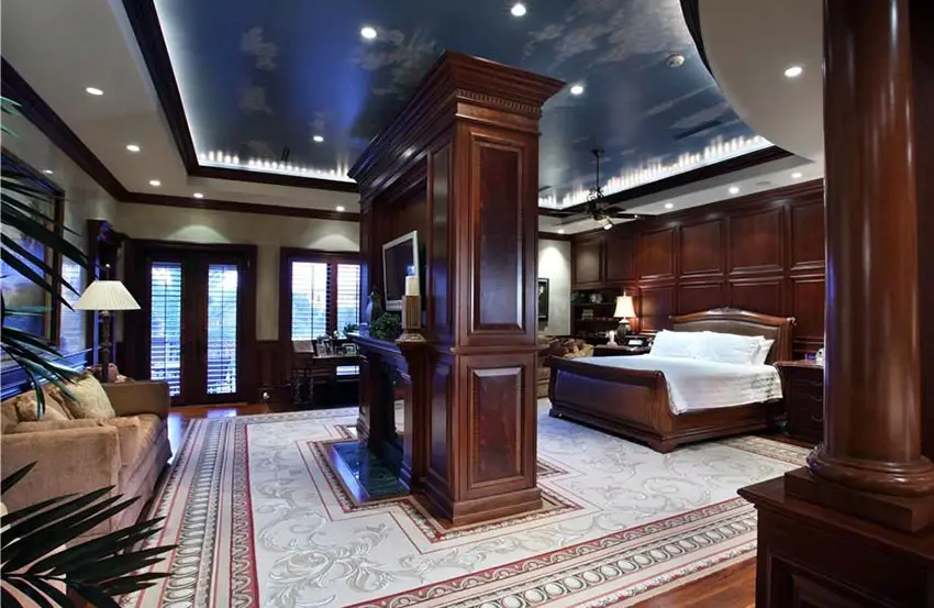 Custom wood panel master bedroom with center fireplace hardwood floors and raised ceiling
