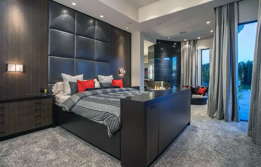 Dark brown theme bedroom with elevated bed, leather headboard and gas fireplace 