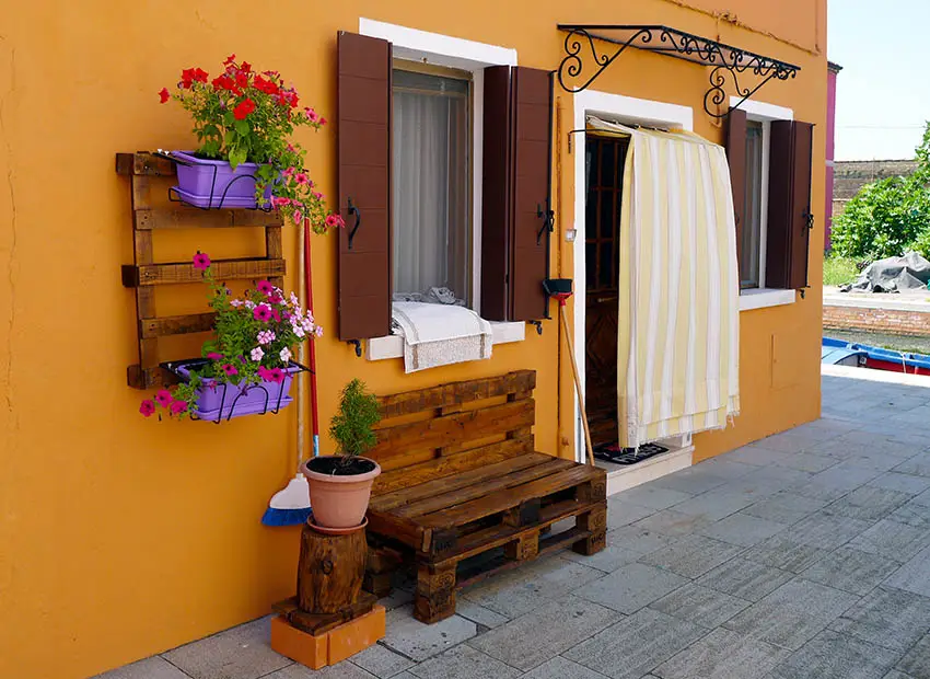 Bench against house wall with flower pots and shutters