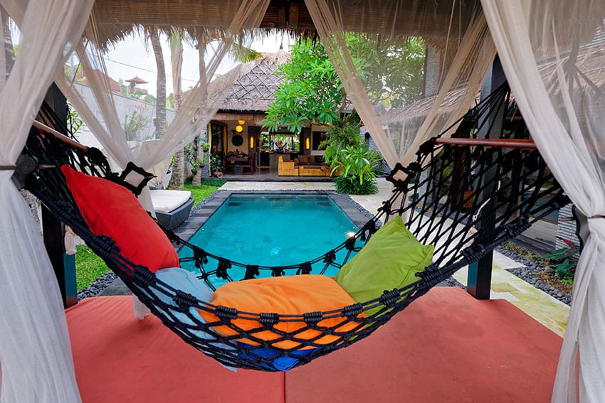 Inside a pool cabana with a hammock and sheer curtains