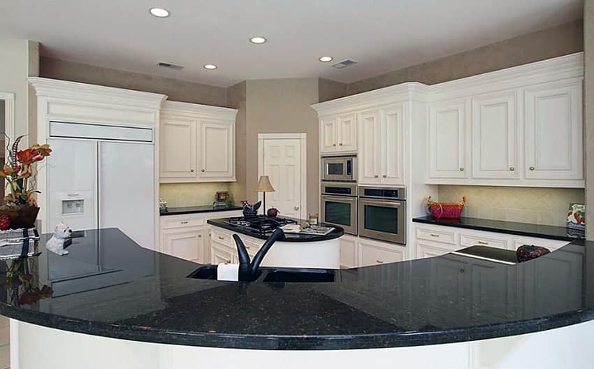 Kitchen with Angola black material counters and white raised panel cabinetry