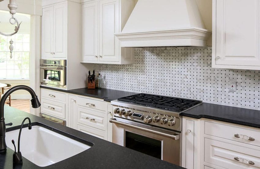  Keuken met zwart granieten aanrecht en witte basketweave backsplash tegel en witte kasten