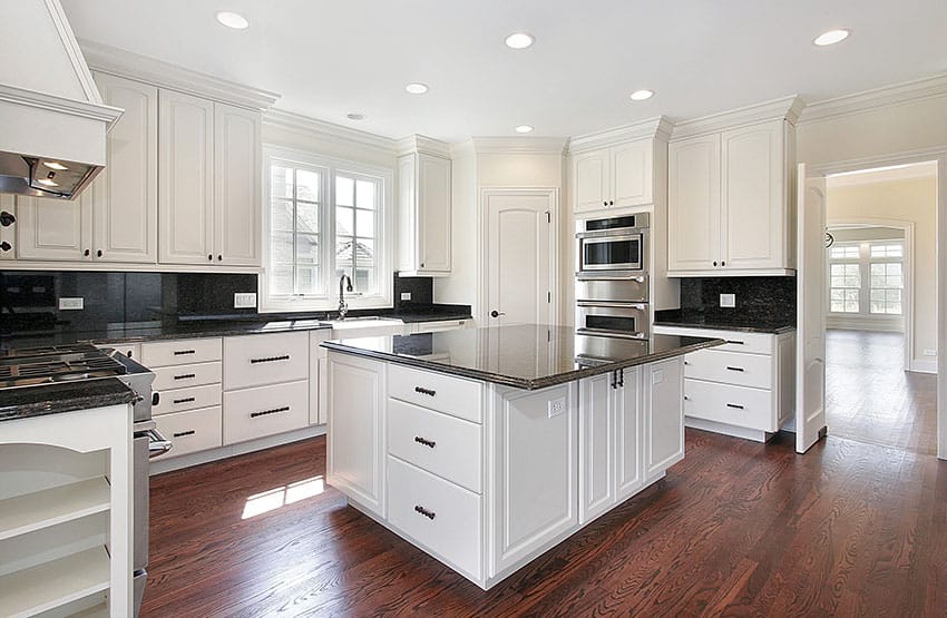 Kitchen with white cabinets and black granite countertops with wood flooring