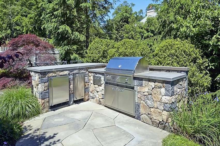 L shaped outdoor kitchen with rough stone
