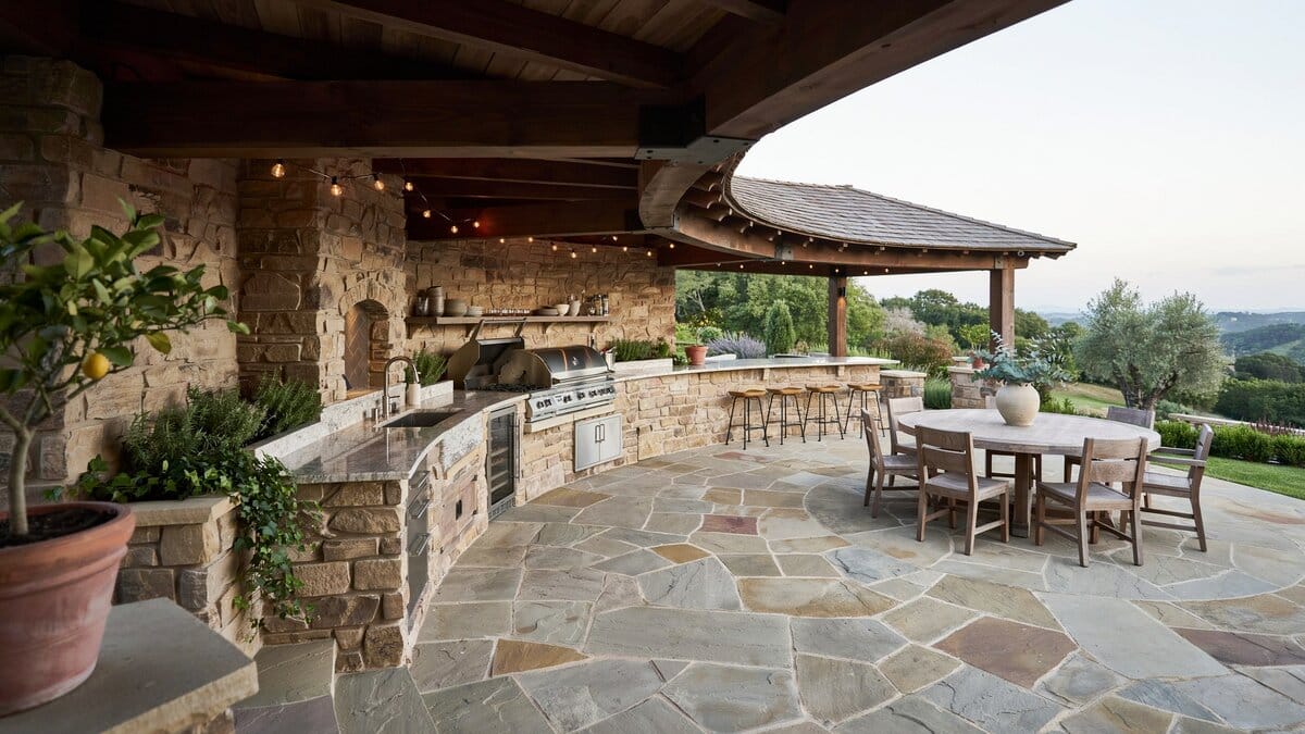Large curved masonry stone counter with bar stools and a round dining end