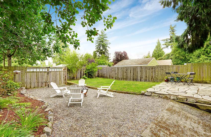 Loose gravel patio with sitting area and flagstone patio in fenced backyard