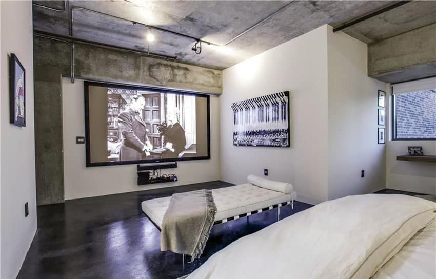 Modern bedroom with exposed concrete walls and projector movie screen