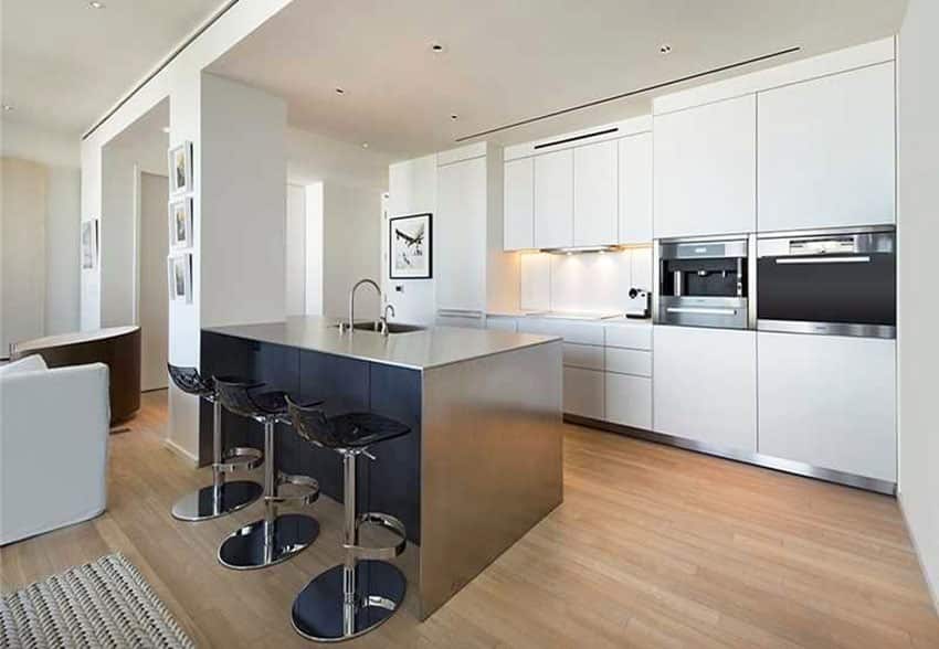 Kitchen with island with chrome finish, three bar stools and modular cabinets