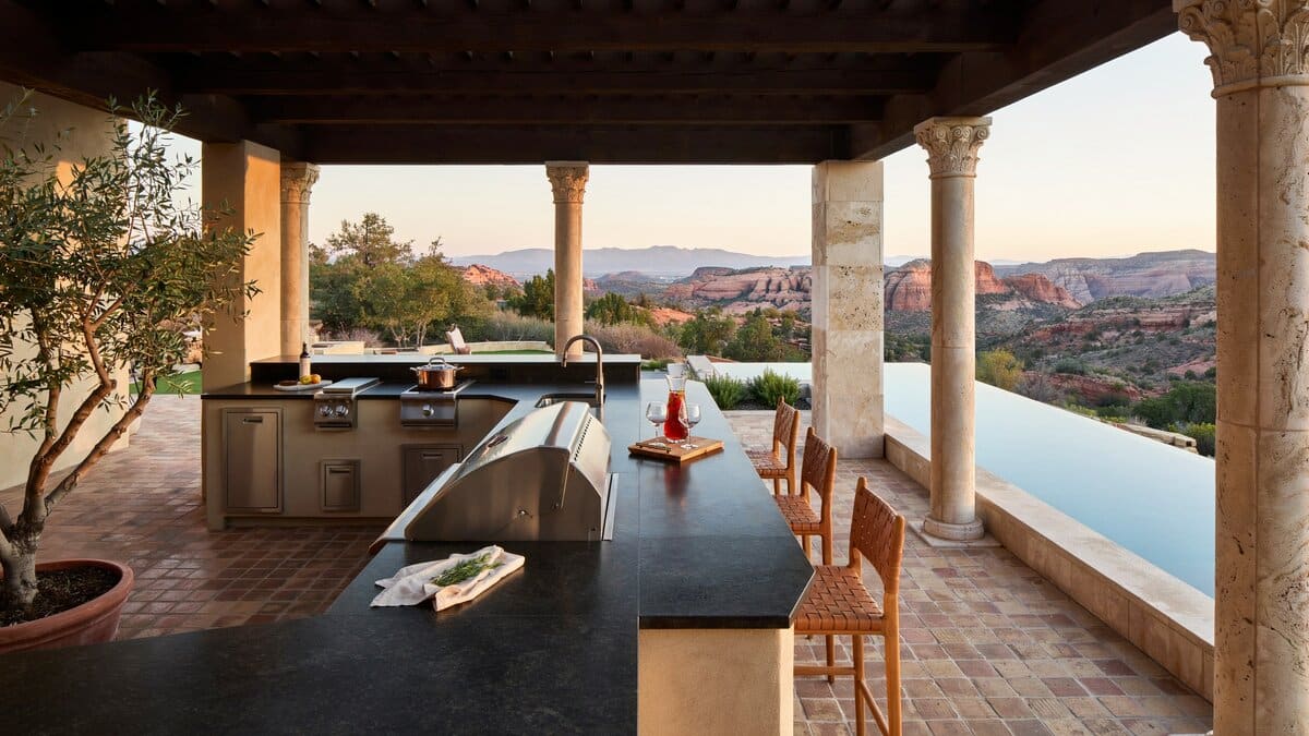 Mediterranean outdoor kitchen with granite L-shaped bar and covered patio near a pool
