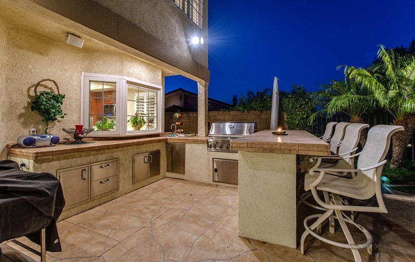 Outdoor kitchen with bar stool seating on stone patio