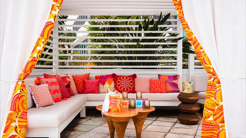 Pool cabana with bright pillows and orange curtains