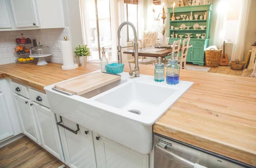 Kitchen with white cabinets, butcher block counters and double sided farmhouse sink