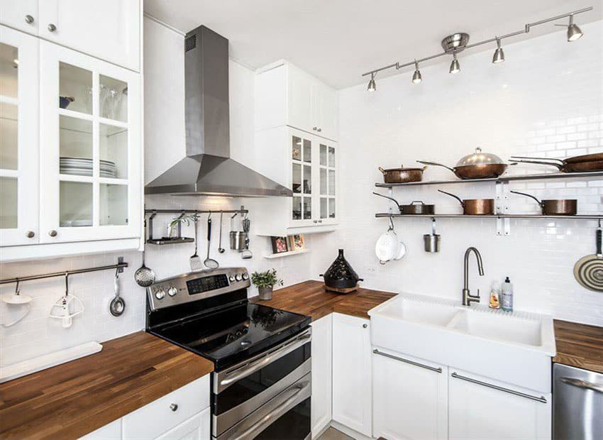 Small country kitchen with white glass door cabinets wood countertop and white subway tile wall