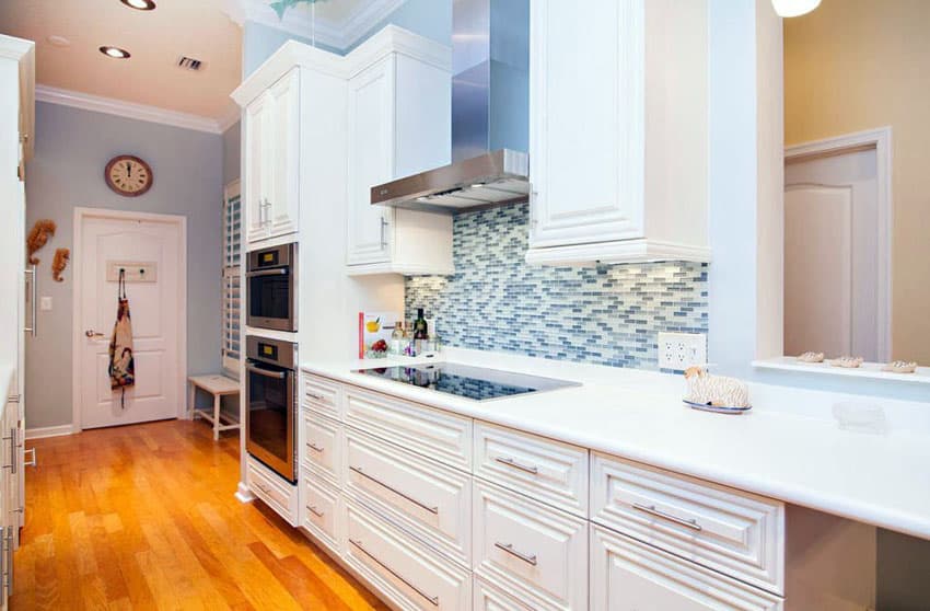 Small galley kitchen with white custom cabinets and mosaic tile backsplash