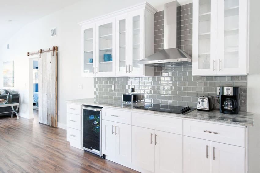 Small one wall kitchen with white cabinets and gray subway tile backsplash