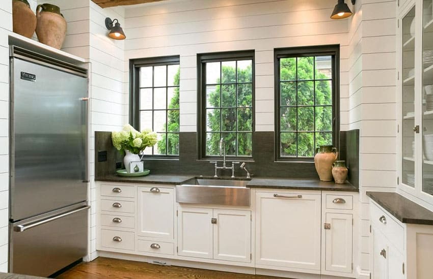 Small u shaped kitchen with white cabinets with glass doors and slate countertops and backsplash