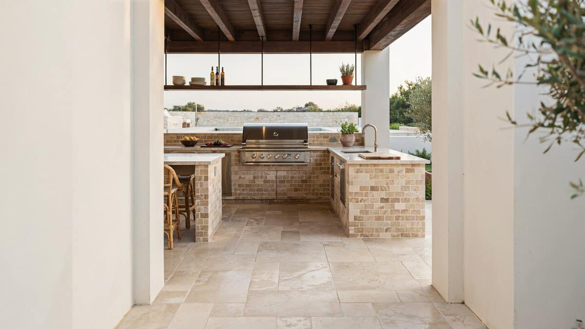 Covered outdoor kitchen with masonry tile cladding and quartzite counters on travertine